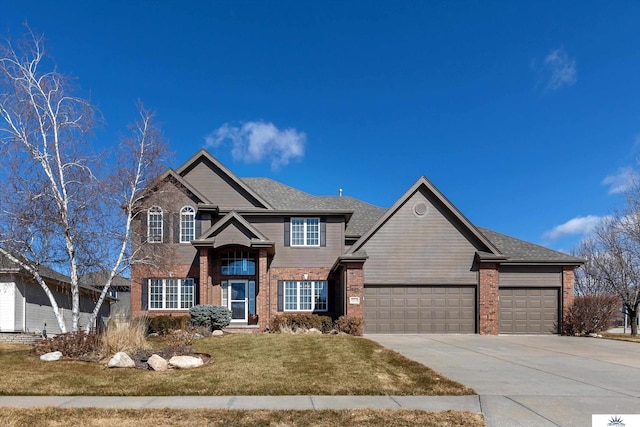 traditional-style home featuring brick siding, a shingled roof, an attached garage, a front yard, and driveway