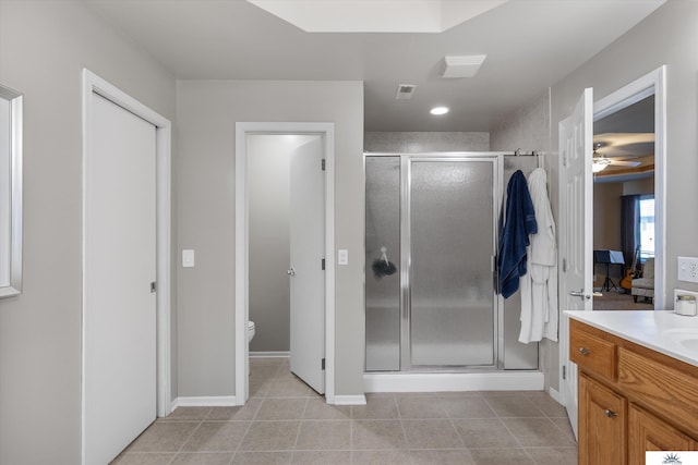 bathroom featuring tile patterned flooring, toilet, vanity, baseboards, and a shower stall