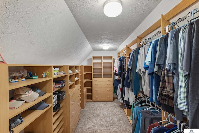 walk in closet with carpet floors and vaulted ceiling