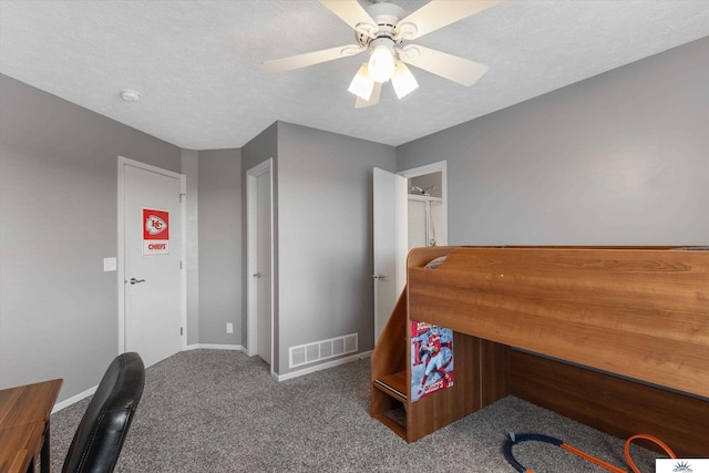 carpeted home office featuring ceiling fan, visible vents, and a textured ceiling