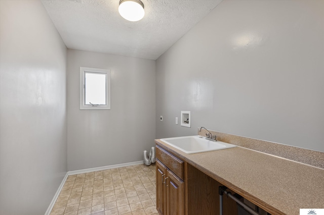 clothes washing area featuring a textured ceiling, hookup for a washing machine, hookup for an electric dryer, a sink, and cabinet space