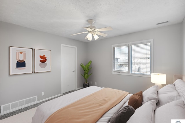 carpeted bedroom with baseboards, ceiling fan, visible vents, and a textured ceiling