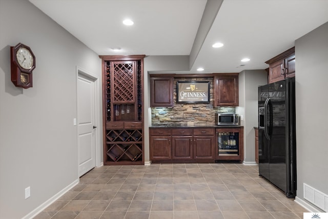 bar with visible vents, wine cooler, stainless steel microwave, black fridge, and backsplash