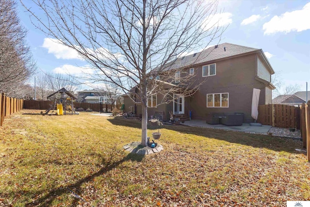 back of house with entry steps, a playground, a fenced backyard, a yard, and a patio area