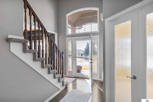 entryway with baseboards, stairway, wood finished floors, a high ceiling, and french doors