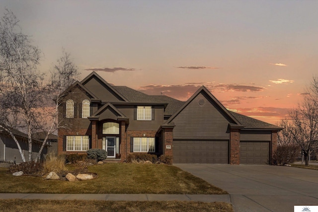 traditional-style house with an attached garage, a front yard, concrete driveway, and brick siding