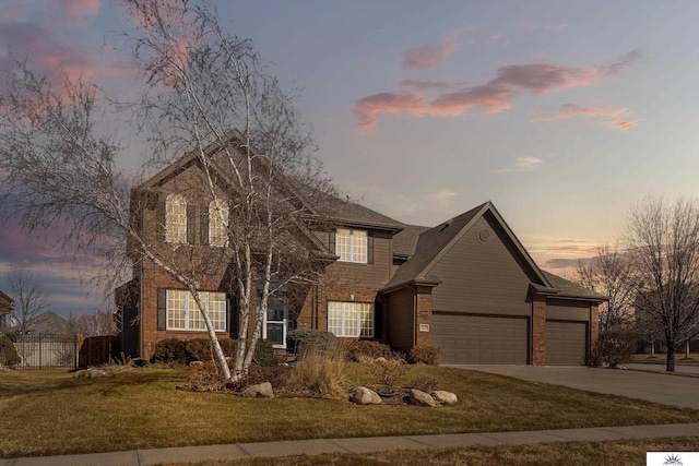 traditional-style home with a garage, brick siding, fence, driveway, and a lawn