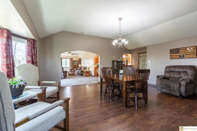 dining space with arched walkways, wood finished floors, ceiling fan with notable chandelier, and lofted ceiling