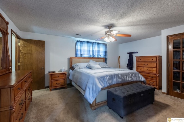 bedroom featuring ceiling fan, visible vents, a textured ceiling, and light colored carpet