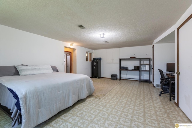 bedroom with a textured ceiling, light floors, and visible vents