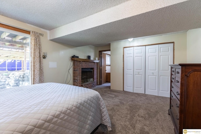 bedroom with a textured ceiling, carpet floors, a closet, and a brick fireplace