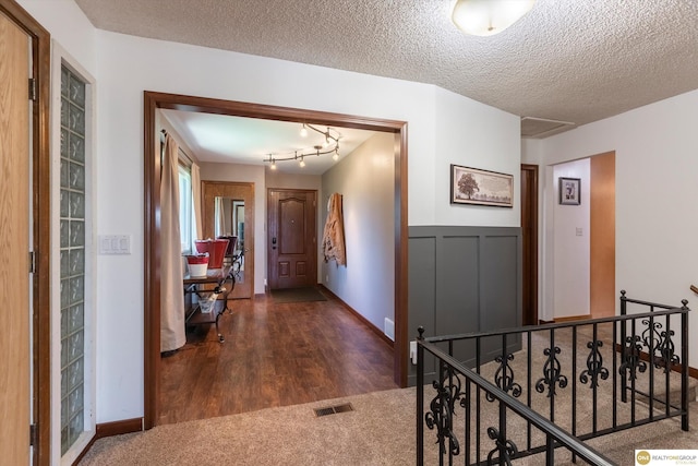 hall featuring dark wood-style floors, visible vents, and a textured ceiling