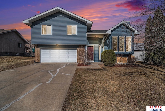 split level home featuring a garage, brick siding, concrete driveway, and a front yard