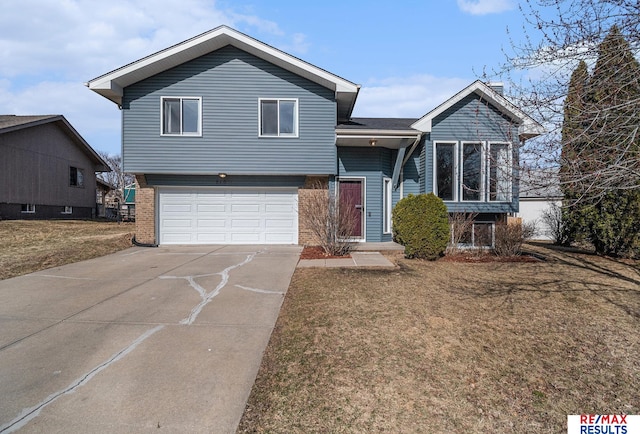 tri-level home with a front lawn, brick siding, a garage, and driveway