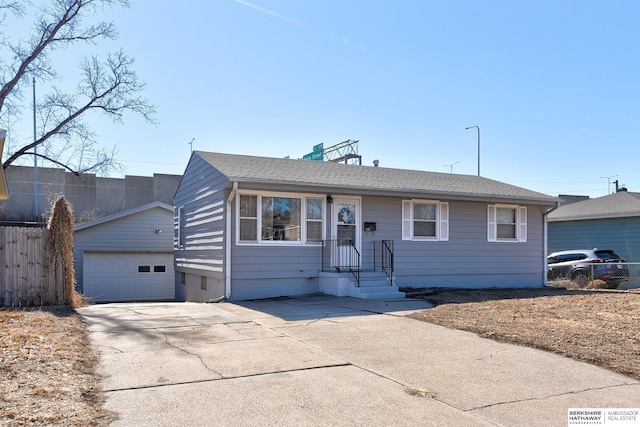 ranch-style house featuring an outbuilding, roof with shingles, a detached garage, concrete driveway, and fence