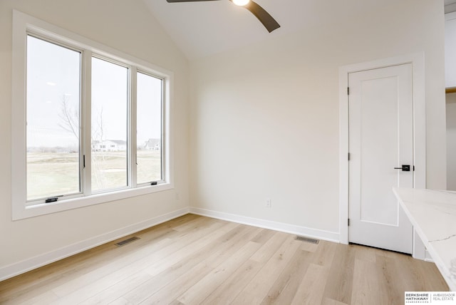 unfurnished room featuring vaulted ceiling, light wood finished floors, visible vents, and baseboards