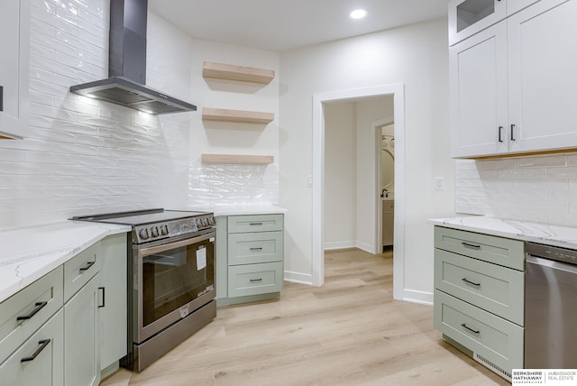 kitchen featuring light stone counters, wall chimney exhaust hood, appliances with stainless steel finishes, light wood-type flooring, and baseboards