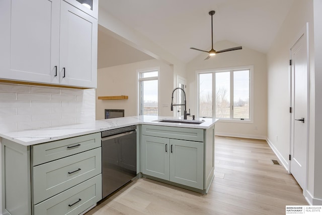 kitchen featuring a peninsula, stainless steel dishwasher, plenty of natural light, and a sink