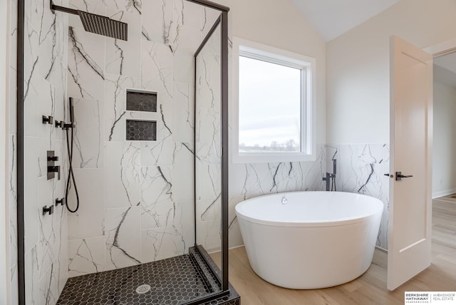 bathroom with vaulted ceiling, wood finished floors, a freestanding tub, and a marble finish shower