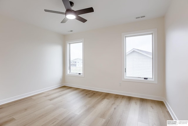 empty room featuring light wood-type flooring, visible vents, and a healthy amount of sunlight