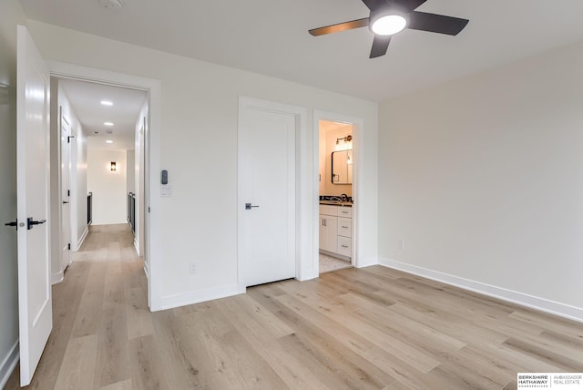 unfurnished bedroom with light wood-style floors, ensuite bath, and baseboards