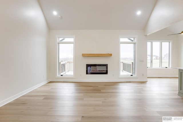 unfurnished living room featuring baseboards, visible vents, a glass covered fireplace, light wood-type flooring, and recessed lighting