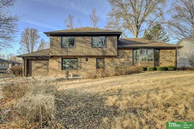 back of house with a garage and brick siding