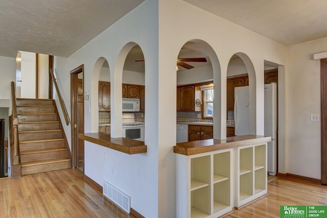 kitchen featuring visible vents, white appliances, backsplash, and light wood-style flooring