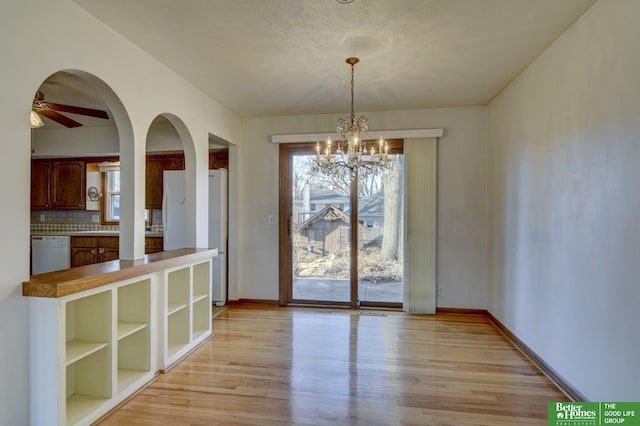 unfurnished dining area featuring arched walkways, a healthy amount of sunlight, and light wood-type flooring