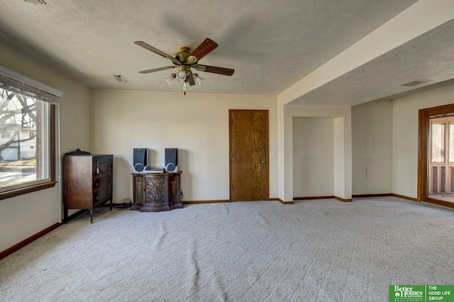 interior space featuring visible vents, a textured ceiling, baseboards, and carpet