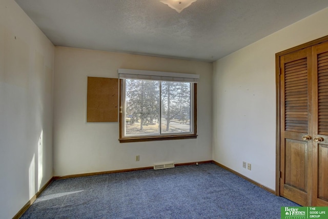 unfurnished bedroom with visible vents, a textured ceiling, a closet, carpet flooring, and baseboards