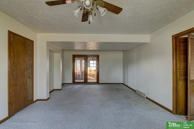 carpeted empty room with visible vents, a textured ceiling, french doors, baseboards, and ceiling fan