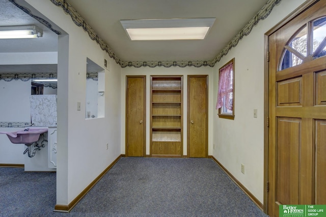 corridor featuring carpet flooring, baseboards, and a sink