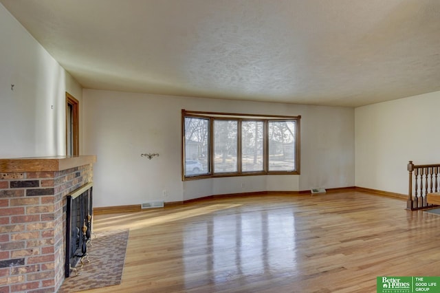 unfurnished living room with visible vents, wood finished floors, and a fireplace