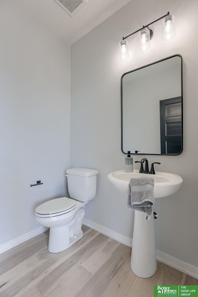 bathroom with toilet, baseboards, visible vents, and wood finished floors