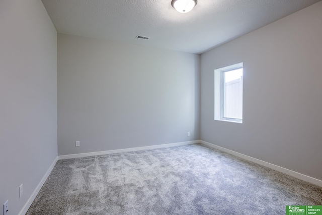 empty room featuring carpet floors, baseboards, visible vents, and a textured ceiling