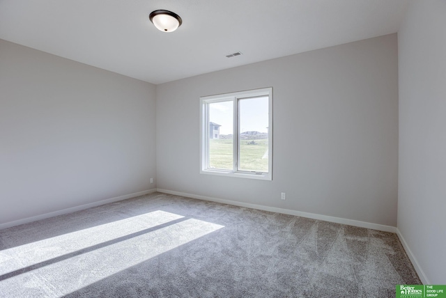 carpeted spare room with visible vents and baseboards