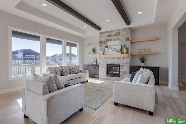 living area featuring light wood-style flooring, a fireplace, baseboards, and beam ceiling