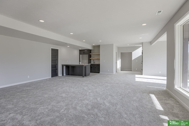 unfurnished living room with light carpet, recessed lighting, and baseboards