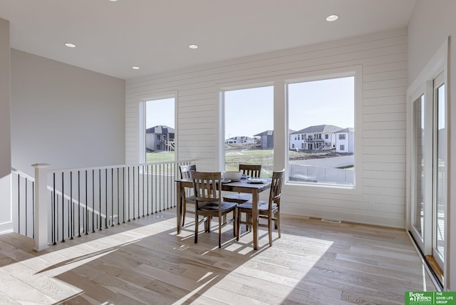 dining room featuring recessed lighting, a residential view, wood walls, and wood finished floors