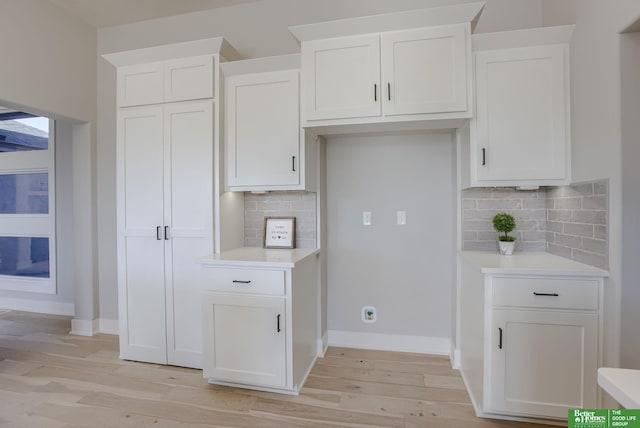 kitchen with light wood finished floors, white cabinetry, and light countertops