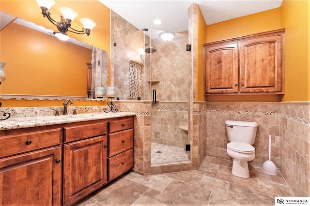 full bath featuring tile walls, toilet, wainscoting, a shower stall, and vanity