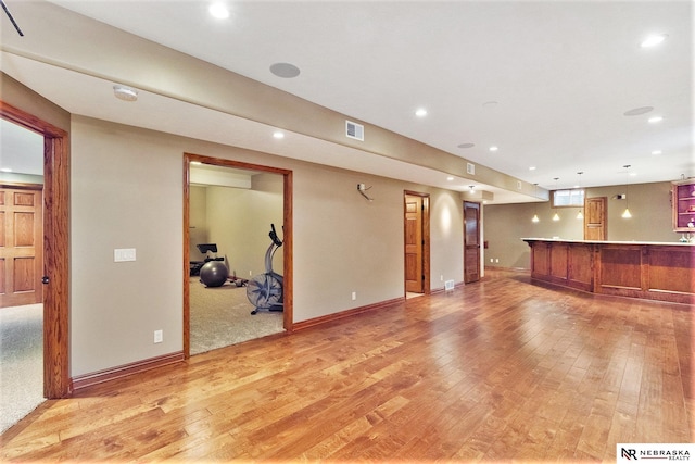 unfurnished living room with light wood finished floors, visible vents, bar area, and recessed lighting