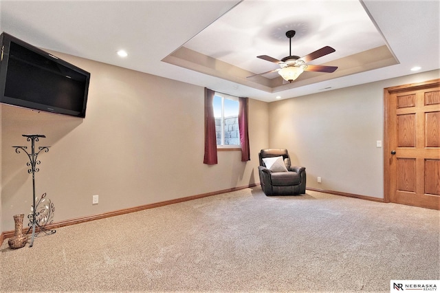 unfurnished room featuring a ceiling fan, a raised ceiling, carpet flooring, and baseboards