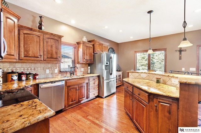 kitchen with stainless steel appliances, light wood-type flooring, a sink, and a healthy amount of sunlight