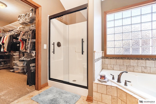 bathroom featuring a bath, a stall shower, a walk in closet, and a wealth of natural light