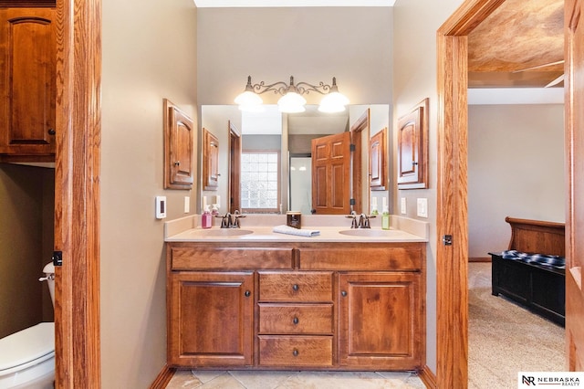 bathroom featuring double vanity, baseboards, toilet, and a sink