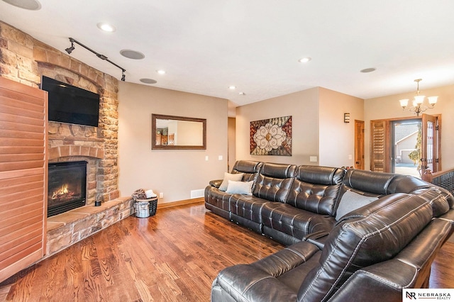 living room featuring a fireplace, recessed lighting, wood finished floors, a chandelier, and baseboards