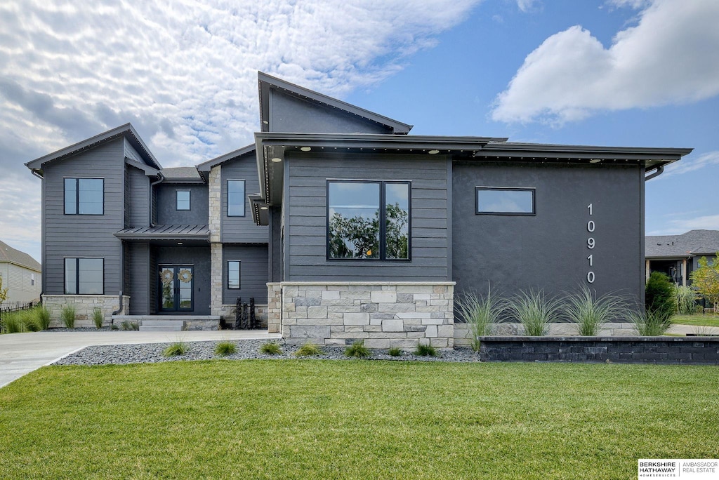 view of front of house featuring stone siding, metal roof, a front lawn, and a standing seam roof