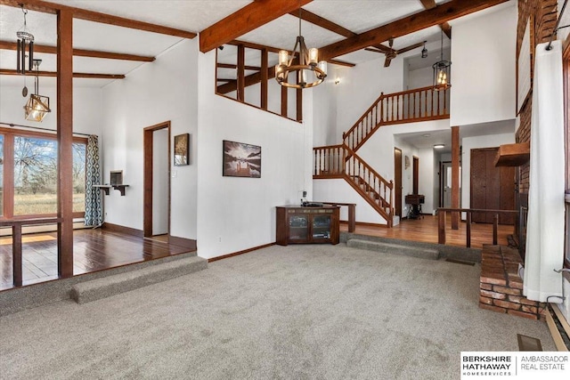 unfurnished living room with baseboards, beamed ceiling, stairs, carpet floors, and a chandelier